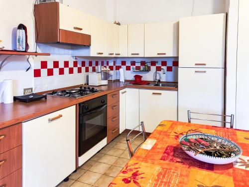 a kitchen with white cabinets and a table with a bowl on it at Villetta a schiera su due livelli con giardino in Metaponto