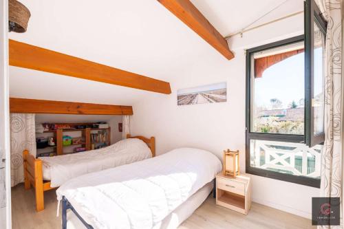 two beds in a bedroom with a window at Maison de vacances à Biscarrosse lac pour 6 personnes in Biscarrosse
