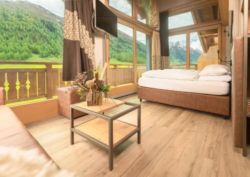 a bedroom with a bed and a table in front of a window at Hotel Amerikan in Livigno