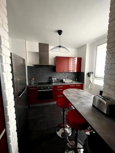 une cuisine avec des placards rouges et des tabourets de bar rouges dans l'établissement Appartement 6p proche plage, climatisé, parking gratuit, à La Seyne-sur-Mer
