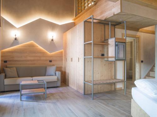 a room with a bed and a couch and a book shelf at Hotel Amerikan in Livigno