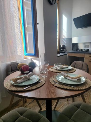 une table en bois avec des assiettes et des verres à vin dessus dans l'établissement Appartement au cœur de ville, à Embrun
