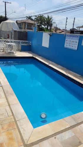 a large blue swimming pool next to a blue wall at Sobrado em Condomínio Praia das Astúrias in Guarujá