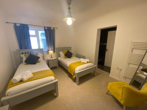 1 dormitorio con 2 camas y silla amarilla en By the beach, with sea views and spectacular sunsets, en Westward Ho