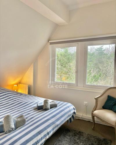 - une chambre avec un lit, une chaise et deux fenêtres dans l'établissement Le Nid Touquettois, à Le Touquet-Paris-Plage