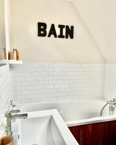 La salle de bains est pourvue d'une baignoire et d'un panneau de lecture. dans l'établissement Le Nid Touquettois, à Le Touquet-Paris-Plage