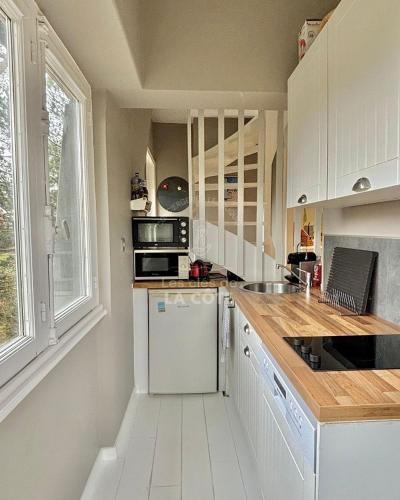 une cuisine avec des armoires blanches et un réfrigérateur blanc dans l'établissement Le Nid Touquettois, à Le Touquet-Paris-Plage