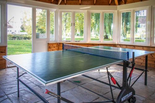 a ping pong table in a room with windows at Windrush Turret Lodge in South Cerney