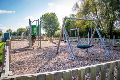 a playground with two swings in a park at Windrush Turret Lodge in South Cerney