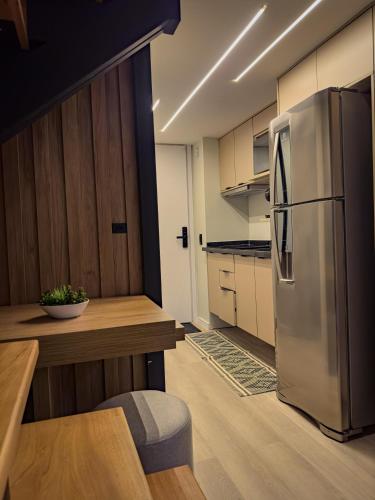 a kitchen with a stainless steel refrigerator and a table at Espaço Versa Brooklin in Sao Paulo