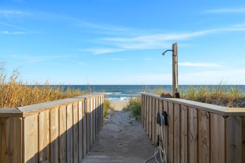 un chemin en bois menant à la plage avec l'océan en arrière-plan dans l'établissement Sea Biscuit, à Surf City