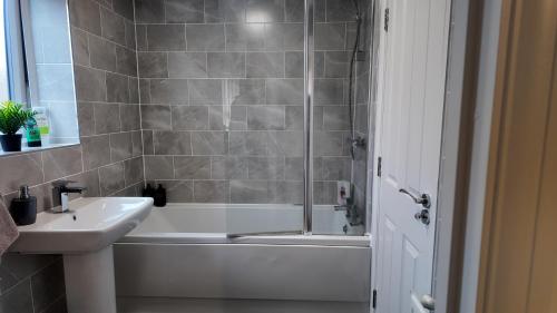 a bathroom with a tub and a sink and a shower at Modern house in City Centre with private parking and gated property in Birmingham