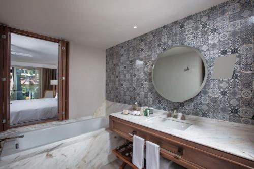 a bathroom with a sink and a mirror and a tub at Krystal Grand Puerto Vallarta - All Inclusive in Puerto Vallarta