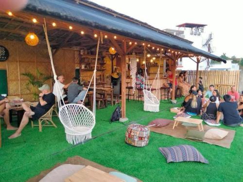 a group of people sitting on the grass under a pavilion at Casa Luntian Lodge and Cafe in Puerto Galera