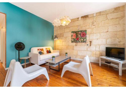 Il comprend un salon doté d'un mobilier blanc et d'un mur en briques. dans l'établissement Appartement en Hypercentre - Le Teulère, à Bordeaux