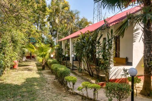 a house with a red roof next to trees at The Wild Orchid Resort Corbett in Rāmnagar