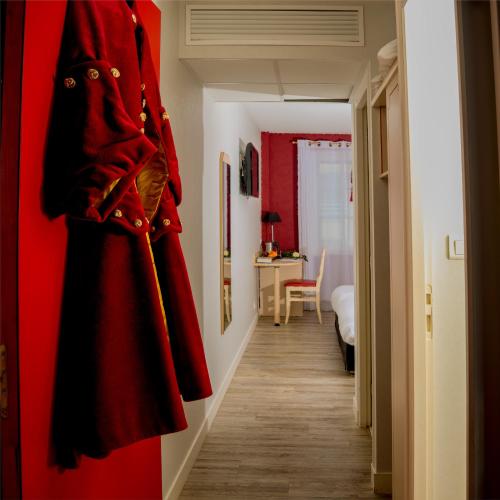 a red coat hanging on a wall in a hallway at Logis Hôtel-Restaurant LE FONTARABIE in Fontenay-le-Comte