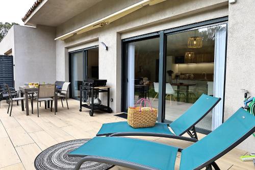 un patio avec deux chaises bleues et une table dans l'établissement U Sognu Superbe T3 neuf à Bonifacio 4 étoiles, à Bonifacio