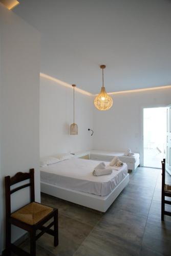 a white bedroom with a large bed and a chair at Casa di Flora in Loutra