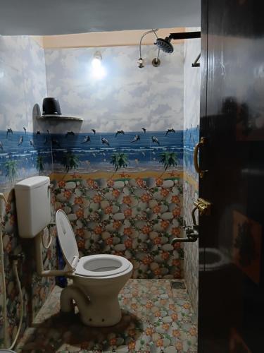 a bathroom with a toilet with a painting on the wall at Home stay in Tiruvannāmalai