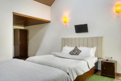 a bedroom with two beds and a tv on the wall at The Wild Orchid Resort Corbett in Rāmnagar