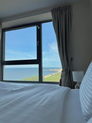 a bedroom with a large window with a view of the ocean at Modern Two Bedroom Apartments in Edinburgh