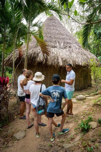 a group of people standing outside of a thatch hut at Taironaka Eco Hotel in Don Diego