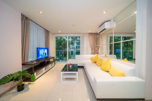 a living room with a white couch and a tv at Patong Kalim Unparalleled Sea View B&B Resort in Patong Beach