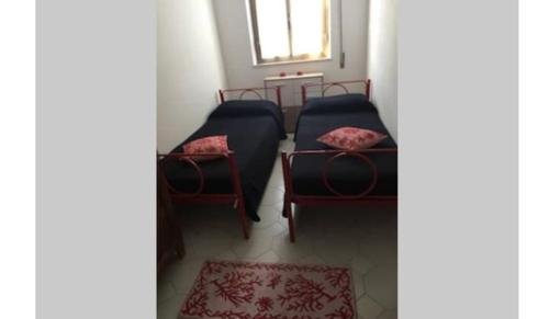 a room with two beds and a table and a window at Casa Monni vista mare in Santa Maria Navarrese