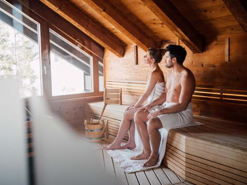 a man and a woman sitting in a sauna at Hotel Der Löwe LEBE FREI in Leogang