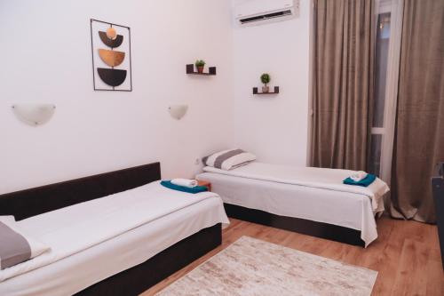 two beds in a room with white walls and wooden floors at BASSO Guest Rooms in Perushtitsa
