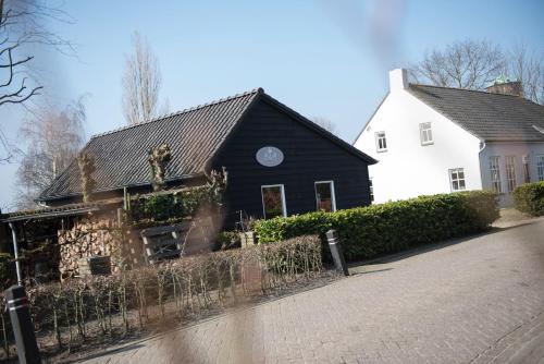 a black and white house with a fence at B&B Logeren bij van Heeren in Made