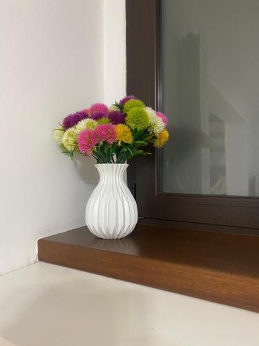 a white vase filled with colorful flowers on a shelf at Largo Zeza Quindici in Boiano