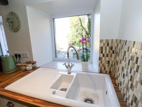 een witte wastafel in een keuken met een raam bij Kirk Yett Cottage in Skipton