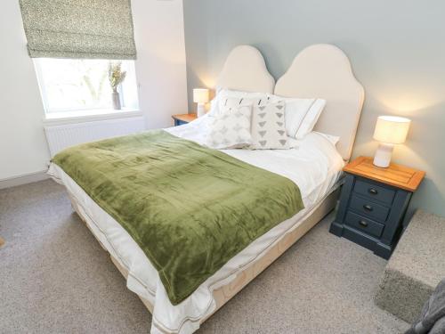 een slaapkamer met een bed met een groene deken erop bij Kirk Yett Cottage in Skipton