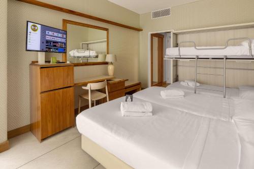 a room with two beds and a desk and a television at B&B Hotel Chioggia Airone in Sottomarina