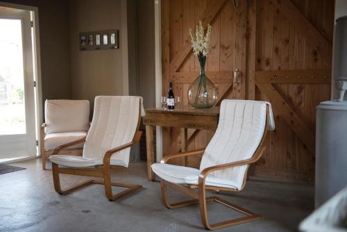 two white chairs and a table in a room at B&B Logeren bij van Heeren in Made