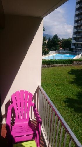 une chaise rose assise sur la terrasse couverte d'une maison dans l'établissement le saphir, à Aix-les-Bains