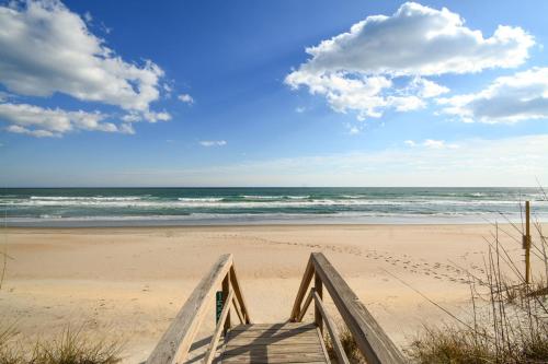 een houten helling naar een strand met de oceaan bij Going Coastal in Surf City