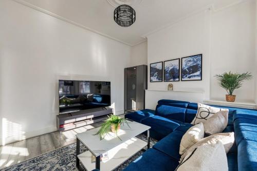 a living room with a blue couch and a tv at Modern 4 Bedroom House In Woodgreen in London