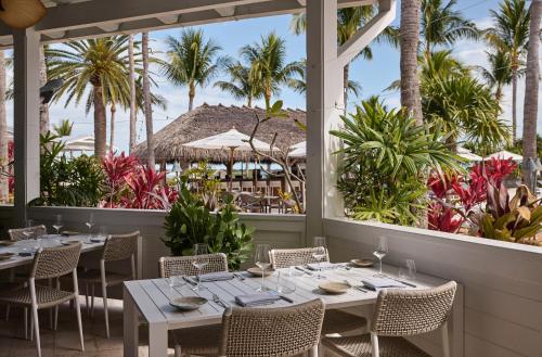 a dining room with tables and chairs and palm trees at Hawks Cay Resort in Marathon