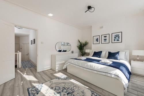 a white bedroom with a large bed and a mirror at Modern 4 Bedroom House In Woodgreen in London