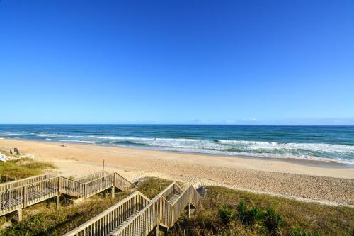 een strand met trappen naar de oceaan bij Oakley's Oasis in Surf City