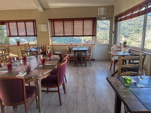ein Restaurant mit Tischen, Stühlen und Fenstern in der Unterkunft Logis Hotel Restaurant Le Grand Puech in Mimet