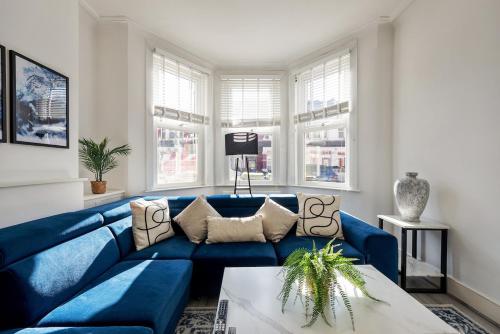 a blue couch in a living room with windows at Modern 4 Bedroom House In Woodgreen in London