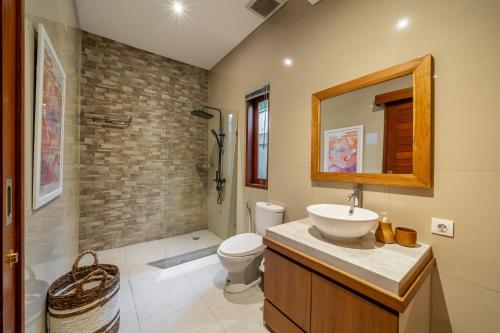 a bathroom with a sink and a toilet and a mirror at Private Pool, Perfect Location -Your Exclusive 3-Bedroom Villa in Canggu -Book Now! in Kerobokan