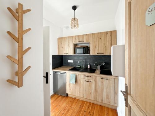 une cuisine avec des armoires en bois et un réfrigérateur dans l'établissement Studio Symphonie des Mers, à Criel-sur-Mer