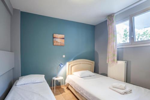 two beds in a room with blue walls and a window at Melitas Sea View Villa in Kassandria