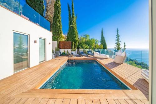 une maison avec une piscine et une terrasse en bois dans l'établissement Villa de luxe avec vue panoramique sur la mer et Monaco, à Roquebrune-Cap-Martin