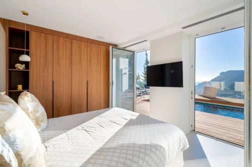 - une chambre avec un grand lit et une porte coulissante en verre dans l'établissement Villa de luxe avec vue panoramique sur la mer et Monaco, à Roquebrune-Cap-Martin